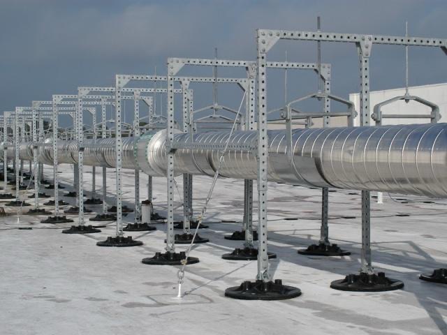 Insulated pipework on H-frame supports standing on rooftop bases